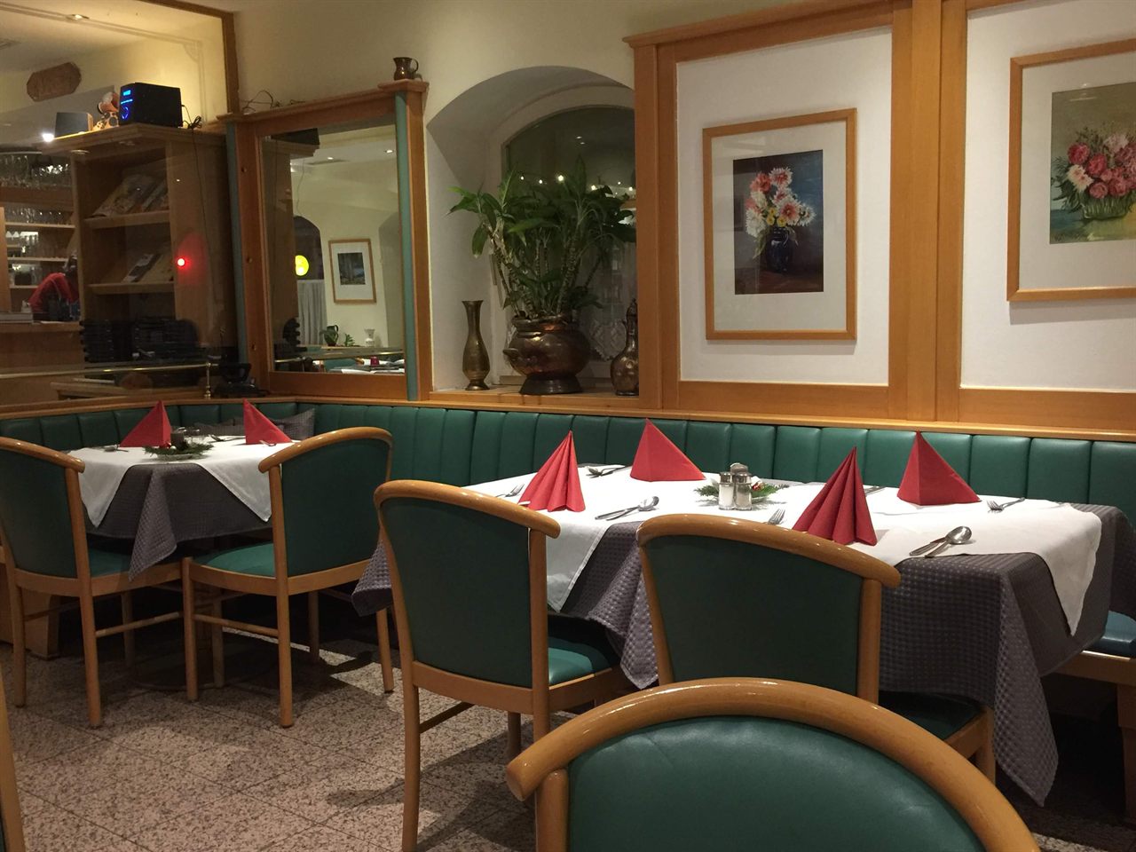 Gedeckte Tische mit grünen Sitzbänken in der Gaststube des Kärntner Eck