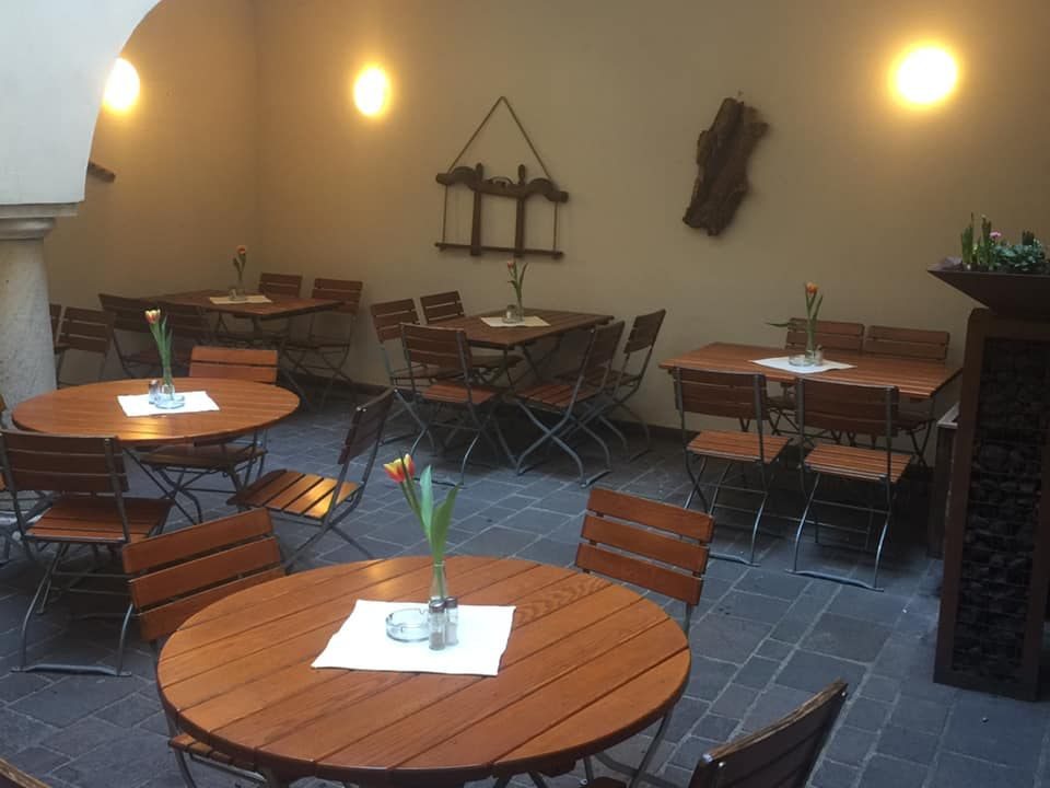 Gemütlicher Innenhof des Kärntner Eck mit Holztischen und warmem Licht